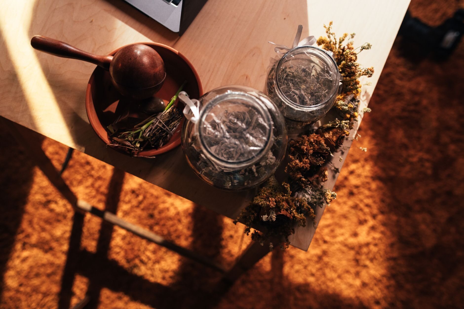 Glass herb jars in late-afternoon sun casting amber shadows across a terracotta floor